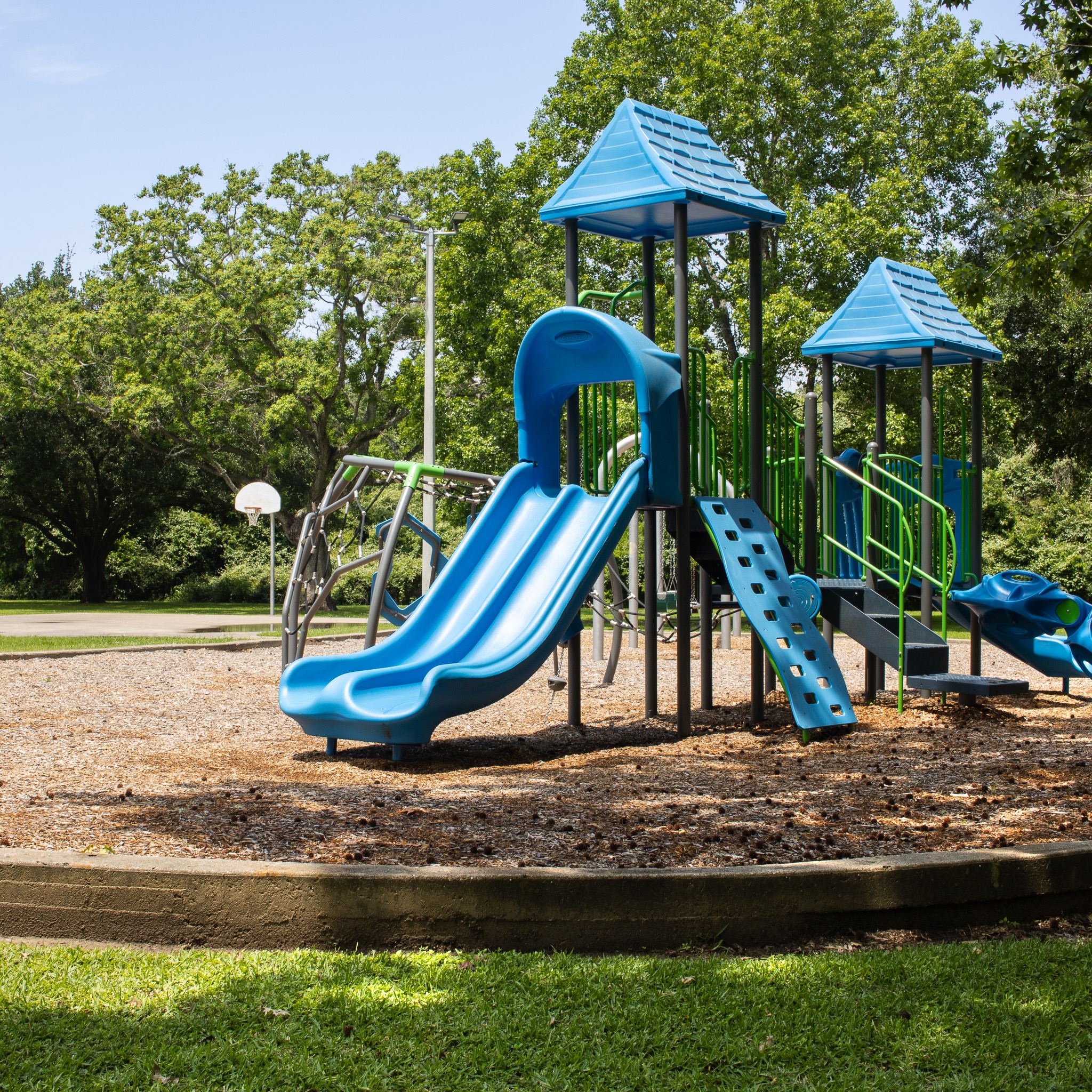 Park playground with basketball court in background