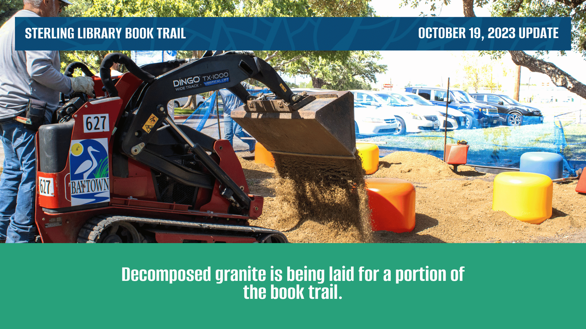A worker uses a front end loader to lay decomposed granite for a new trail walkway